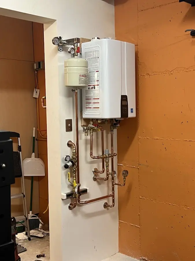 Plumbing technician inspecting water heater connections in Newport